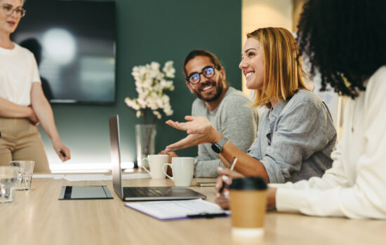Business woman talking to her colleagues during a meeting in a boardroom ¿Te reúnes con tu equipo presencialmente tras el retorno de verano?